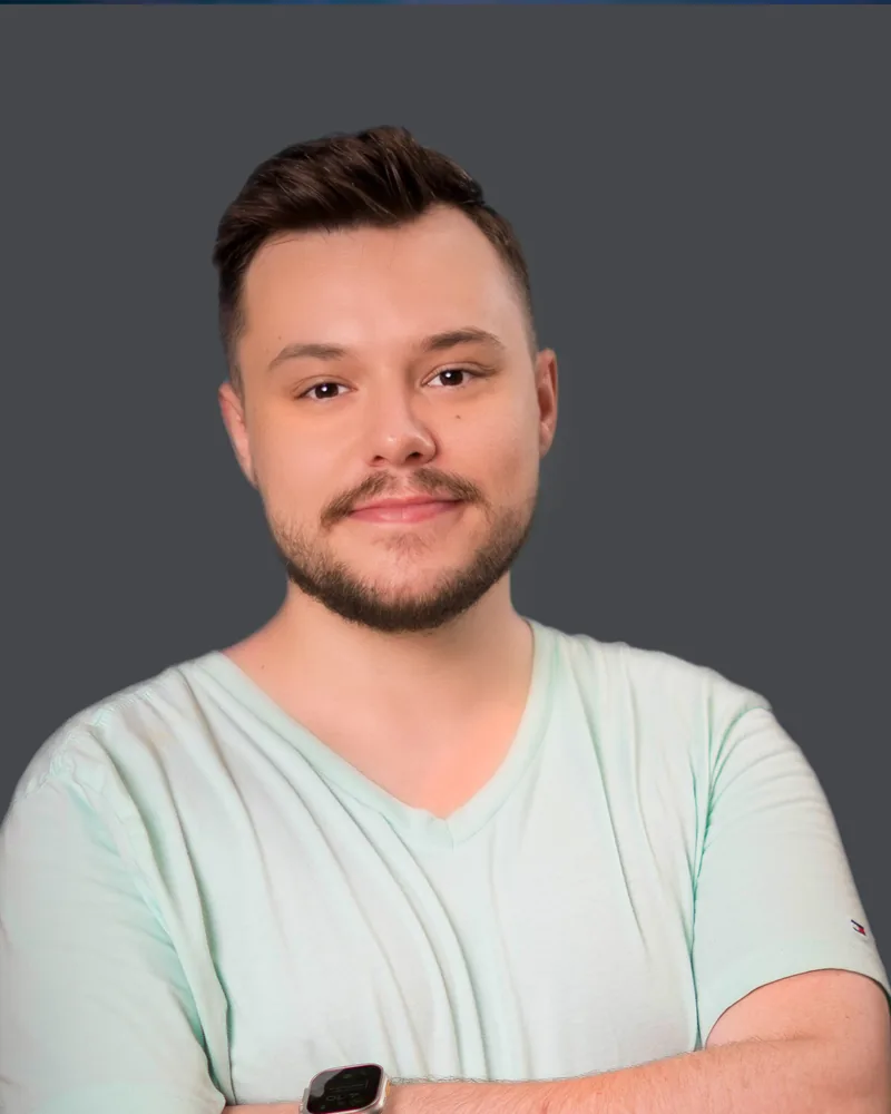 Jeremy Bish casual headshot in a mint t-shirt with arms folded against a grey backdrop